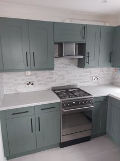 a kitchen with green cabinets and white counter tops