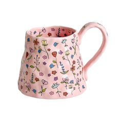 a pink mug with flowers painted on it