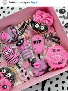 a pink box filled with lots of different types of cupcakes on top of a table