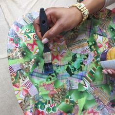 a person is using a paintbrush to decorate a table cloth with colorful designs on it