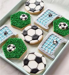 decorated cookies in the shape of soccer balls and goalies are on a baking sheet