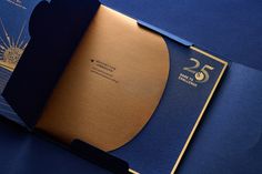 an open blue folder with gold foil on the front and back cover, sitting on a blue surface