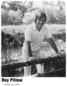 a black and white photo of a man leaning on a fence with his hand on the rail