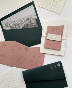 the wedding stationery is laid out on top of each other, including pink and green envelopes