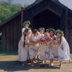 a group of women in white dresses standing next to each other with wreaths on their heads