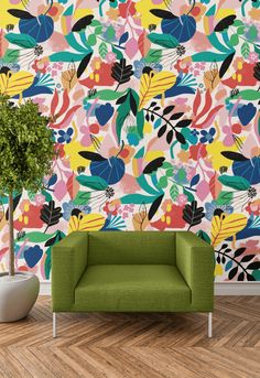 a green chair sitting in front of a colorful wallpaper with leaves and flowers on it