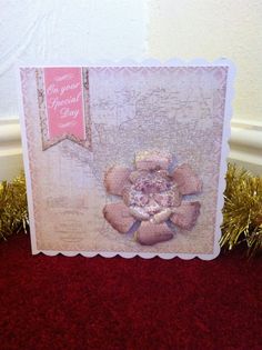 a card with a pink flower on it sitting on top of a red carpeted floor