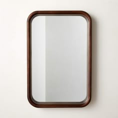 a mirror mounted to the side of a wall next to a wooden framed object on top of a white wall