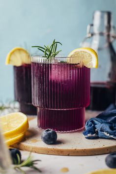 two glasses filled with blueberry lemonade and rosemary garnish