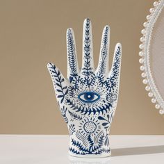 a blue and white ceramic hand with an eye on it's palm next to a chair