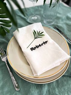 a white plate topped with two napkins next to a green table cloth and silverware