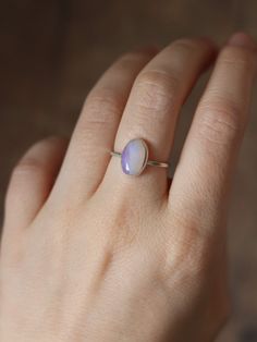 This dainty and extremely delicate ring features a beautiful Australian Lightning Ridge opal, set in a fine silver bezel with open back. The band is made with a sterling silver square wire. Size 6Handmade It's a perfect everyday ring - simple, yet full of character. Can be stacked and combined with other rings or worn by itself, for a more minimalist look. Delicate purples make each opal absolutely unique, with its own stunning colours and inclusions. The look of the gemstone changes in differen Oval Solitaire Opal Ring In Sterling Silver, Minimalist Everyday Jewelry With Cabochon, Minimalist Everyday Cabochon Jewelry, Dainty Stackable Sterling Silver Opal Ring, Delicate Opal Gemstone Rings, Dainty Handmade Oval Opal Ring, Minimalist Opal Rings With Gemstone, Minimalist Sterling Silver Cabochon Moonstone Ring, Dainty Silver Opal Stackable Ring