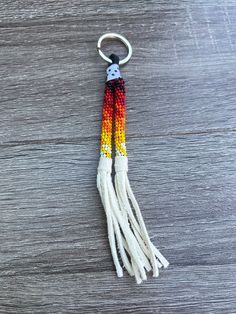 an orange, yellow and white tasseled keychain sitting on top of a wooden table