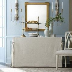 a dining room with blue walls and white table cloths on the side, two chairs in front of an ornate mirror