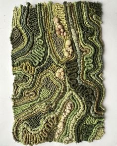 a piece of art made out of green and brown yarn with buttons on the side