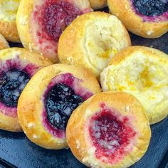 several pastries with blueberries and jam are on a black plate, ready to be eaten