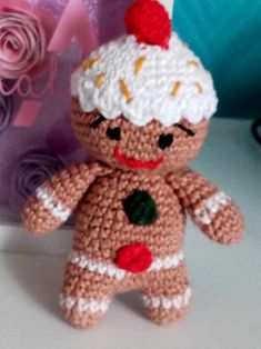 a crocheted ginger doll next to a pink rose