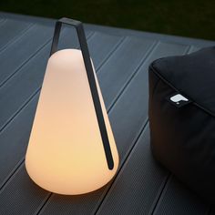 a white lamp sitting on top of a wooden table next to a black bean bag