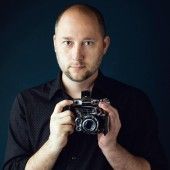 a man holding up a camera in front of his face and looking at the camera