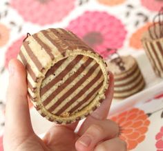 a person holding up a cookie in front of some cupcakes