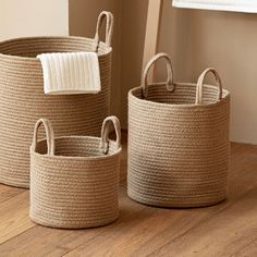 three woven baskets on the floor with towels in them