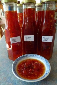 three jars filled with red sauce sitting on top of a table