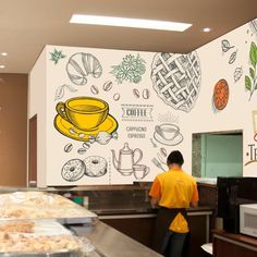 a man standing in front of a counter filled with pastries and coffee cups on the wall