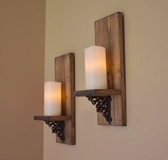 two candles are lit on the wooden wall sconces