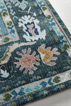 an area rug with blue, green and pink flowers on the bottom is laying on top of a white surface