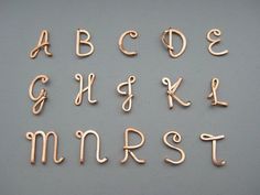 the letters and numbers are made out of copper colored wire on a gray surface with scissors