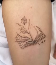 a tattoo on the leg of a woman with an open book and a plant growing out of it