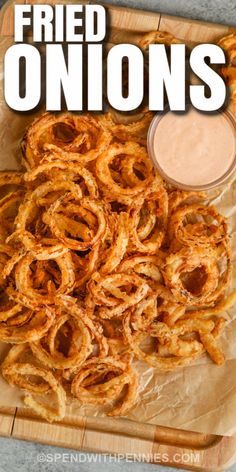 fried onion rings on a cutting board with dipping sauce in the middle and text overlay