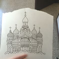 a person holding up a piece of paper with a drawing of a church on it