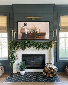 the fireplace is decorated with greenery, candles and a painting on it's mantle