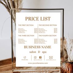 a price list is displayed in front of a vase with dried flowers on the table