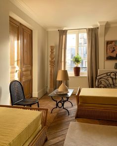 a bedroom with two beds, a chair and a table in front of a window