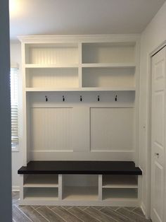 an empty room with white shelves and black bench