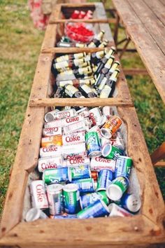 an old wooden wagon filled with cans and cans of soda on top of green grass