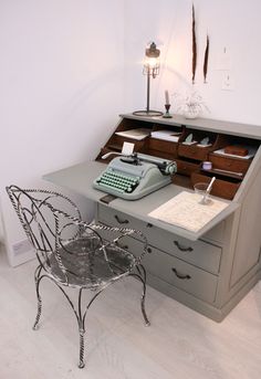 an old fashioned desk with a chair and typewriter