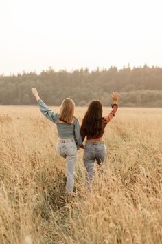 two women walking through tall grass towards the woods