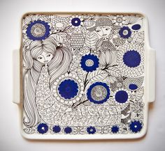 a blue and white plate with an image of two women surrounded by flowers on it