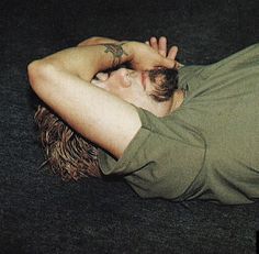 a young man laying on the floor with his head in his hands and eyes closed