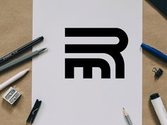 a piece of paper with the letter r on it surrounded by pens and pencils