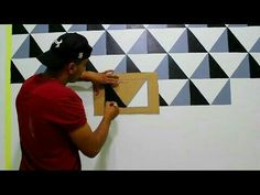 a man is painting a wall with black and white triangles on the wall behind him