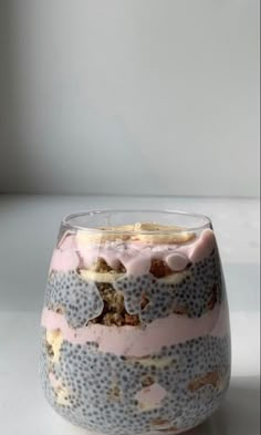 a pink and blue glass with some food inside it on a table next to a white wall