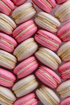 many pink and white macaroons are arranged together