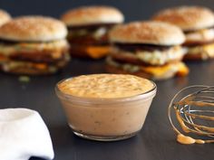 a table topped with sandwiches and a small glass bowl filled with sauce next to it