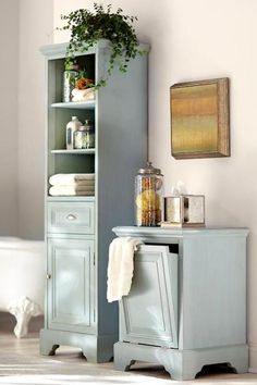 a bathroom with a blue cabinet next to a white bath tub and a potted plant