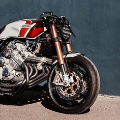 a red and white motorcycle parked next to a wall