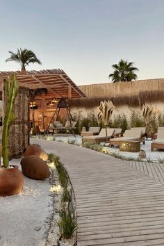 a wooden walkway leading to an outdoor lounge area with palm trees on the other side